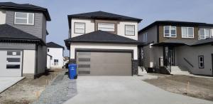 a house with a garage and a driveway at Luxurious 2 bedroom basement suite in Winnipeg