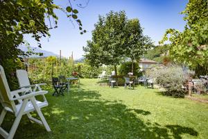 un prato con sedie e tavoli in un cortile di Casa Martello a Levico Terme