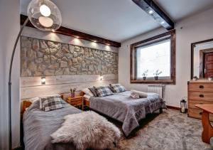 a bedroom with two beds and a stone wall at Willa Weronika in Zakopane