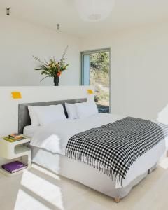 a white bedroom with a large bed and a vase of flowers at Les Milles Roches in Gordes