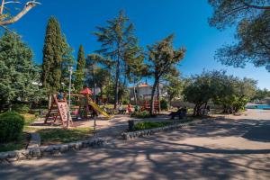 een park met een speeltuin met een glijbaan bij Apartments house Pinezic in Malinska