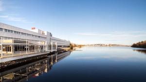 - un grand bâtiment à côté d'une étendue d'eau dans l'établissement Finlandia Hotel Alba, à Jyväskylä