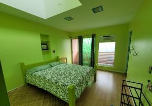 een groene slaapkamer met een bed en een raam bij The Big Island Hostel in Hilo