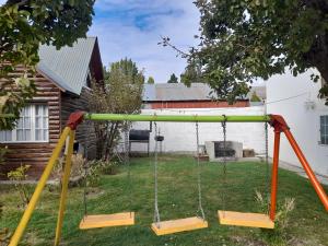 a swing set in a yard with a house at Cabañas Matices in El Calafate