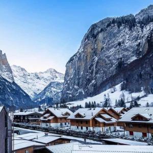 uma cidade com edifícios cobertos de neve em frente a uma montanha em Ferienwohnung Talhaus em Lauterbrunnen