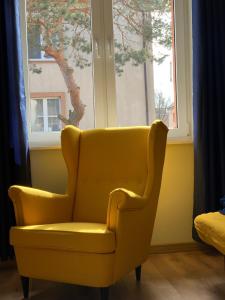 a yellow chair sitting in front of a window at Kapitański Hel in Hel