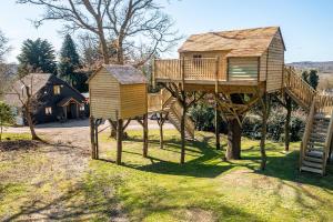 a tree house with a deck and a ladder at Oakside Tree Tops in Canterbury