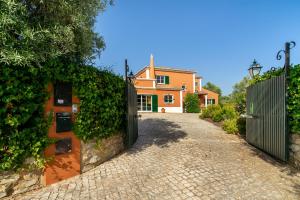 an orange house with a gate and a driveway at Quinta das Figueiras - Bordeira - Faro in Bordeira
