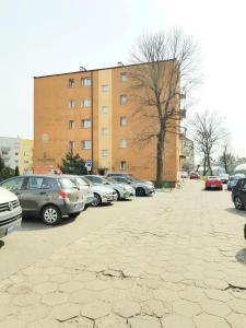 un estacionamiento con autos estacionados frente a un edificio en Apartament Modrzewskiego, en Grudziądz