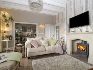a living room with a couch and a fireplace at High Rigg Garden Cottage in How