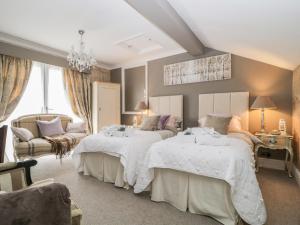 a bedroom with two beds and a couch at High Rigg Garden Cottage in How