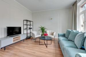 a living room with a blue couch and a tv at Lion Apartments - Capri in Sopot