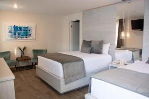 Cette chambre d'hôtel comprend deux lits, une table et des chaises. dans l'établissement Hotel Monumental, à Aguascalientes