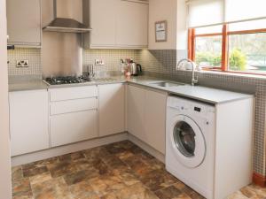 a white kitchen with a washer and dryer at Eskview Cottage in Whitby