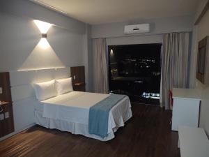 a hotel room with a bed and a window at Hotel Quartzo in Cristalina