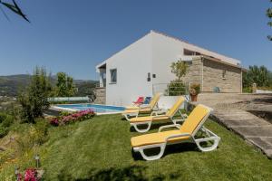 a group of chairs sitting on the grass by a pool at QUINTA DOS MONTEIROS - 3 Quartos com Piscina in Resende