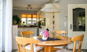 una cocina con una mesa de madera con sillas y un jarrón de flores en Skipperhus, en Ahrenshoop