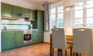 een keuken met groene kasten en een tafel en stoelen bij Friederike in Ahrenshoop