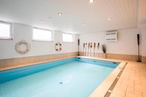 a large swimming pool with blue water in a room at Strandleben 11 - Hans Kinder in Ahrenshoop
