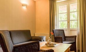 a living room with a table and a chair and a table and a window at Meermaler in Ahrenshoop