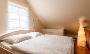 ein Schlafzimmer mit einem weißen Bett und einem Fenster in der Unterkunft Alte Tischlerei 01 in Wustrow