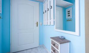 a blue hallway with a white door and a mirror at Marikens Deel in Ahrenshoop
