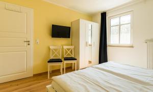a bedroom with two chairs and a tv on the wall at Strandhaus Gabriella 02 in Ahrenshoop +21 photos