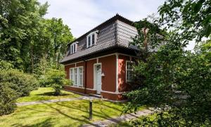 a small red house in the middle of a yard at Villa Sonnenfrieden 01 in Ahrenshoop