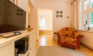 een woonkamer met een flatscreen-tv en een stoel bij Villa Sonnenfrieden 02 in Ahrenshoop