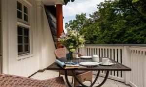 einen Tisch mit Tellern und Blumen auf dem Balkon in der Unterkunft Villa Sonnenfrieden 02 in Ahrenshoop