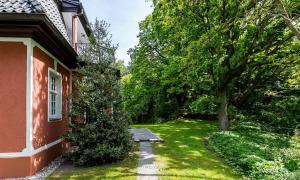 een tuin naast een rood huis met een boom bij Villa Sonnenfrieden 02 in Ahrenshoop