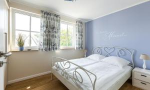 a bedroom with a white bed with a blue wall at Haus Seeschwalbe in Ahrenshoop