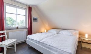 a bedroom with a large white bed and a window at Boddenzauber 02 in Wieck