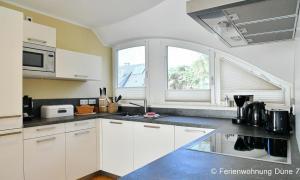 a kitchen with white cabinets and a window at Düne 7 in Dierhagen