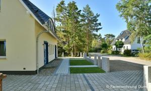 a house with a brick sidewalk next to a building at Düne 7 in Dierhagen