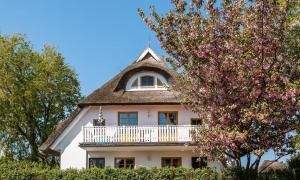 Casa blanca grande con balcón y árbol en Ahrenshooper Landhaus 04, en Ahrenshoop