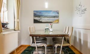 einen Esstisch mit Stühlen und ein Gemälde an der Wand in der Unterkunft Worpswede in Ahrenshoop