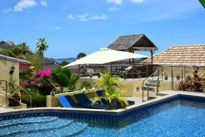 a pool with chairs and an umbrella next to a house at Angelot Villa in Chaweng Noi Beach