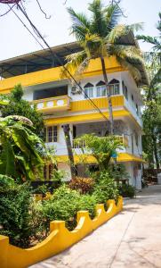 een geel gebouw met een palmboom ervoor bij The Lost Hostel, Varkala - Helipad in Varkala