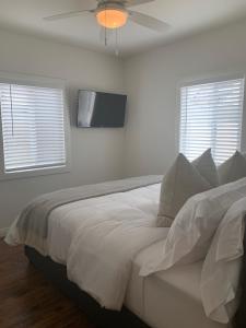 a bedroom with a white bed with a ceiling fan at Huntington Highlight - Pool, Patio, Close To Beach in Huntington Beach