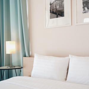 una cama con sábanas blancas y una lámpara en una mesita en Palm Crescent Hua Hin, en Cha Am