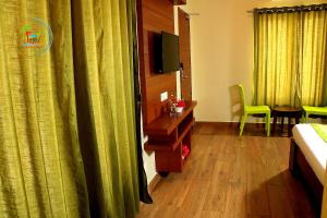 a hotel room with a bed and a tv and curtains at Tranquil Park in Pondicherry