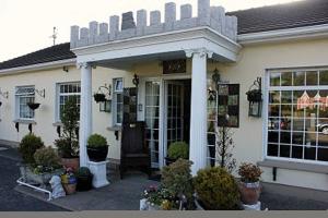 un magasin à l'avant d'une maison avec une terrasse couverte dans l'établissement Bunratty Castle Mews B&B, à Bunratty