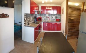 een keuken met rode kasten en een houten tafel bij Au ti bonheur d'en O ' in Le Lambert