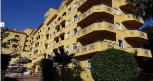 a large yellow building with bushes in front of it at Hotel VistaMar in Benalmádena