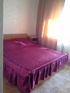 a purple bed in a bedroom with a window at Роза in Lazarevskoye