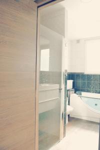 een badkamer met een glazen deur naar een bad bij Villa Maredan in Oostende