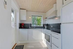 een witte keuken met witte kasten en een raam bij Dejlig feriebolig med havudsigt i naturskønt område in Munkebo