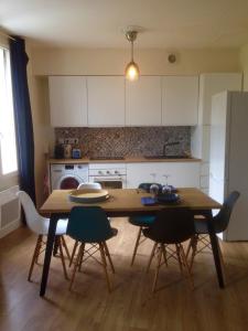 a kitchen with a wooden table and chairs and a kitchen with white cabinets at Joli Appartement Le Gutenberg T2 4p Quartier Mirabeau Proche Gare in Tours