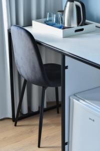 uma cadeira preta sentada numa secretária com uma mesa branca em Atelier Boutique Hotel em Shkodër